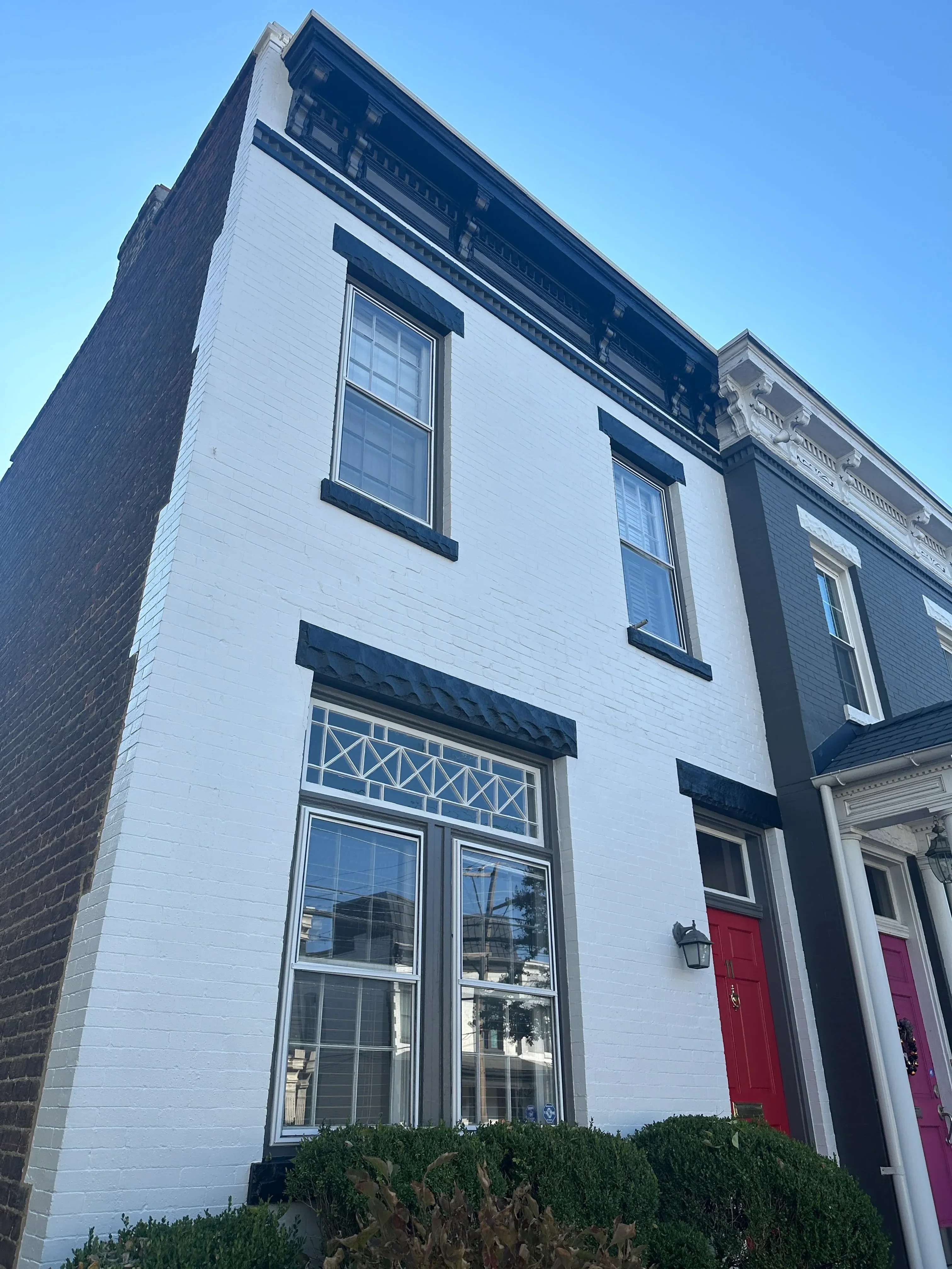 White painted residential exterior with dark trim, multiple windows, and metal roofing