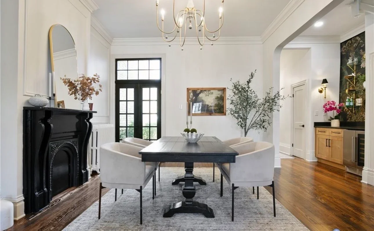 White painted dining room with black fireplace, crown molding, and coffered ceiling details