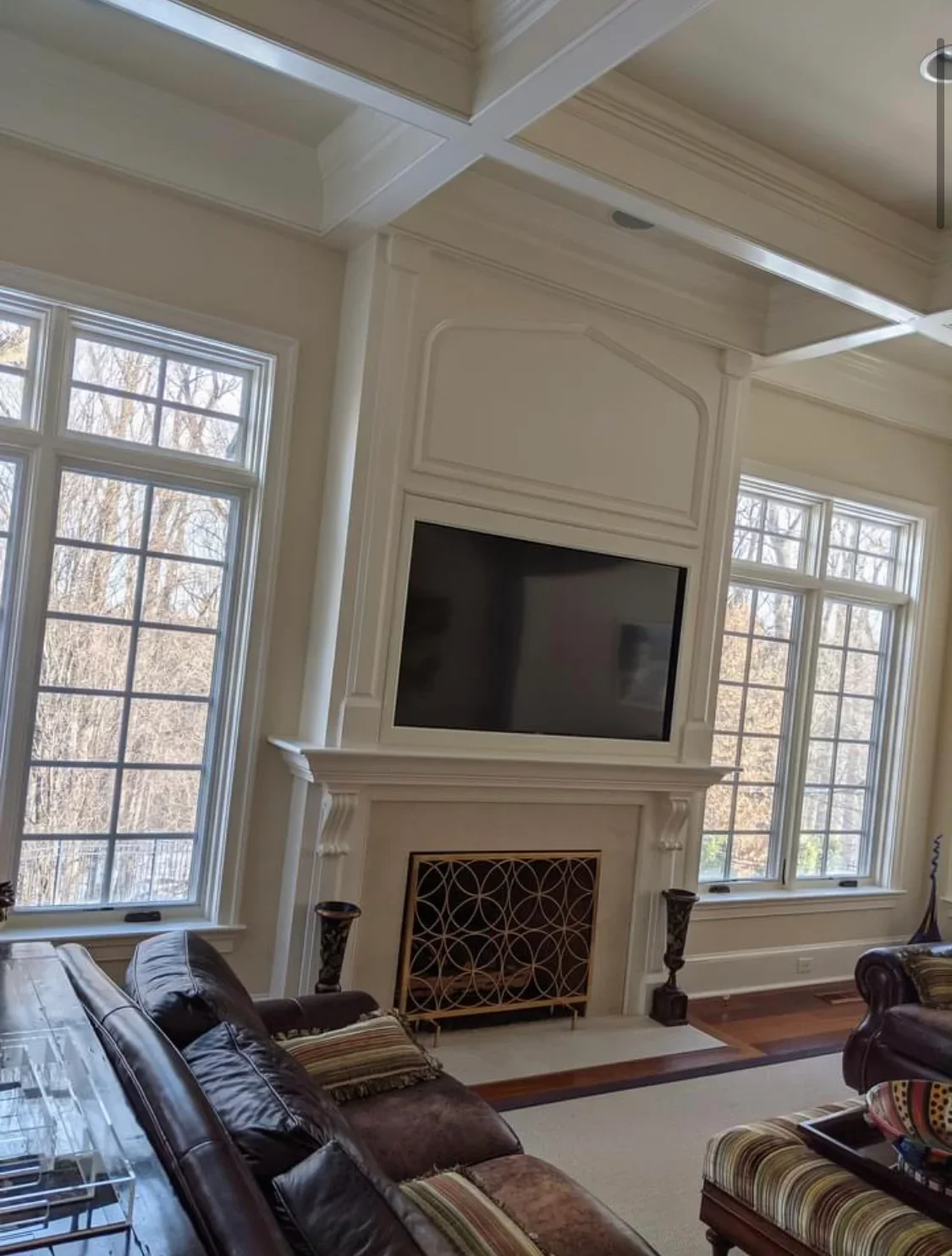 White coffered ceiling and fireplace surround with raised panel trim in elegant living room