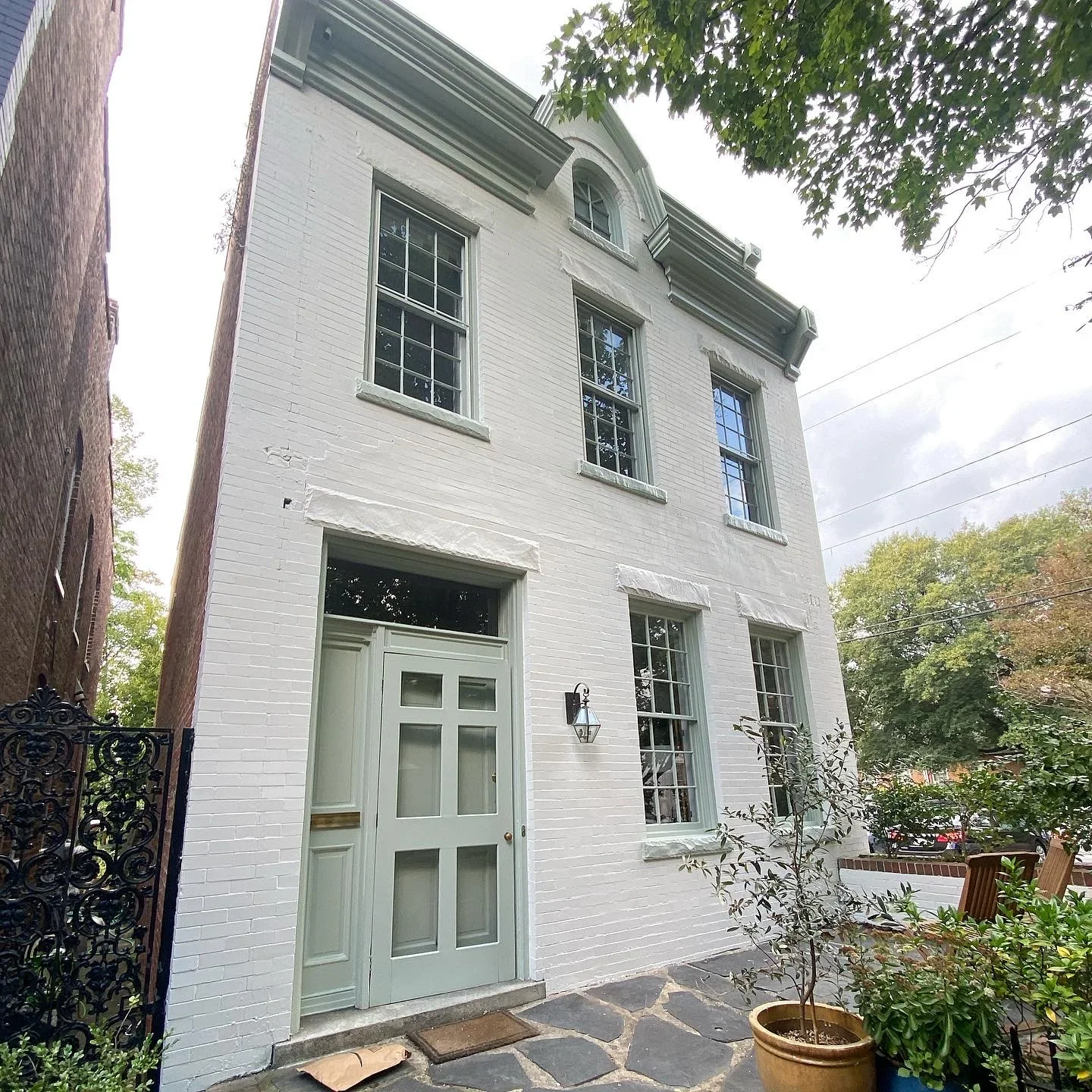 White painted brick facade with green trim door and multi-pane windows on historic building