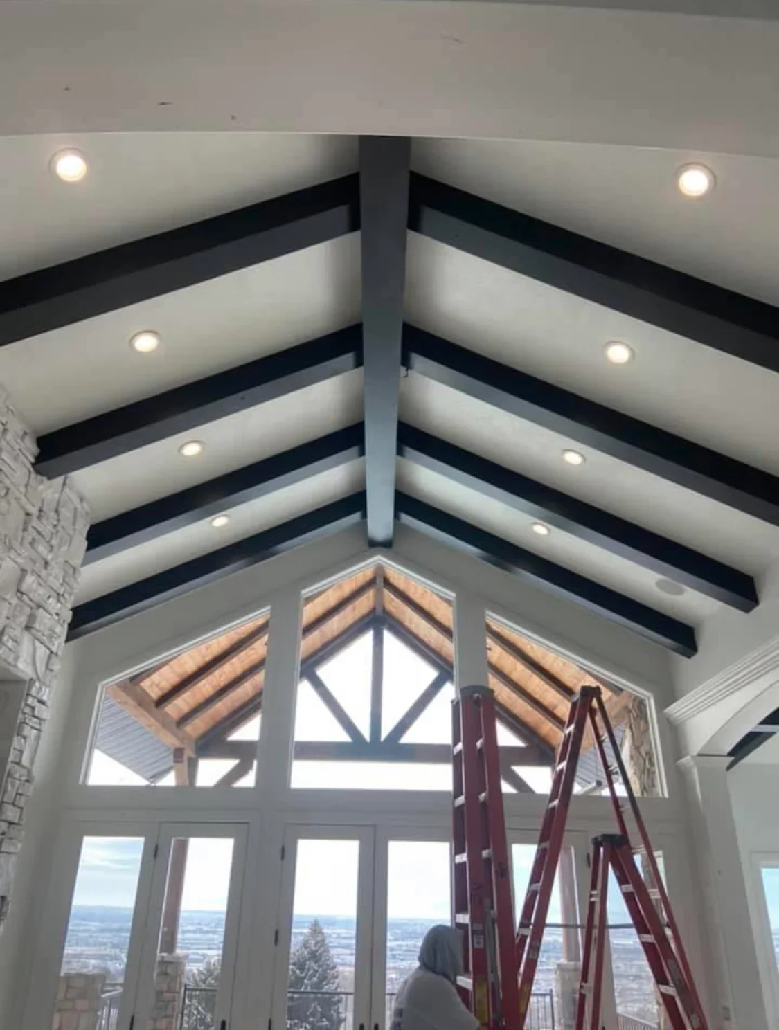 White vaulted ceiling with black beam stripes, exposed wood rafters, and recessed lighting fixtures
