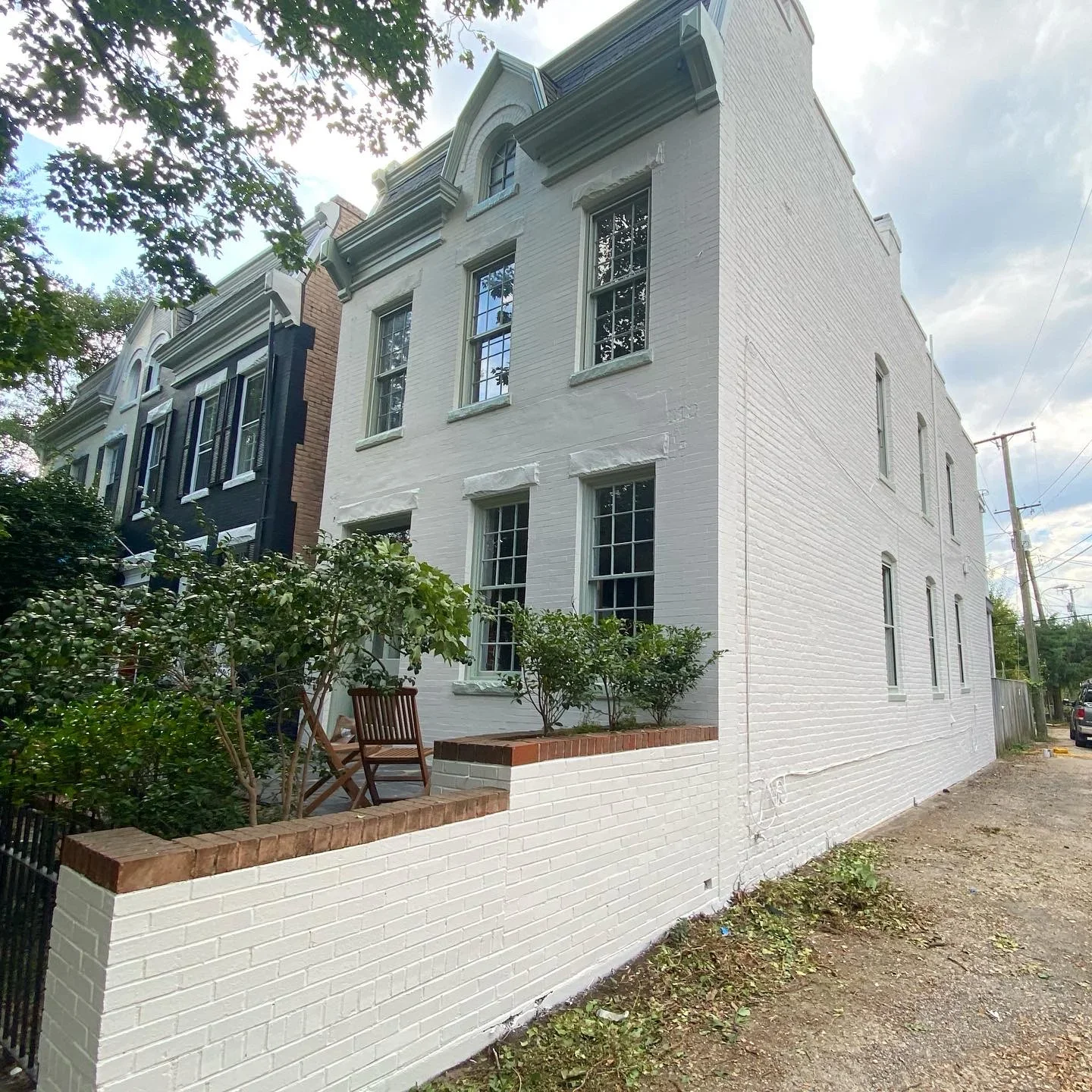 White painted brick exterior with red brick trim, multi-pane windows, and mansard roof details