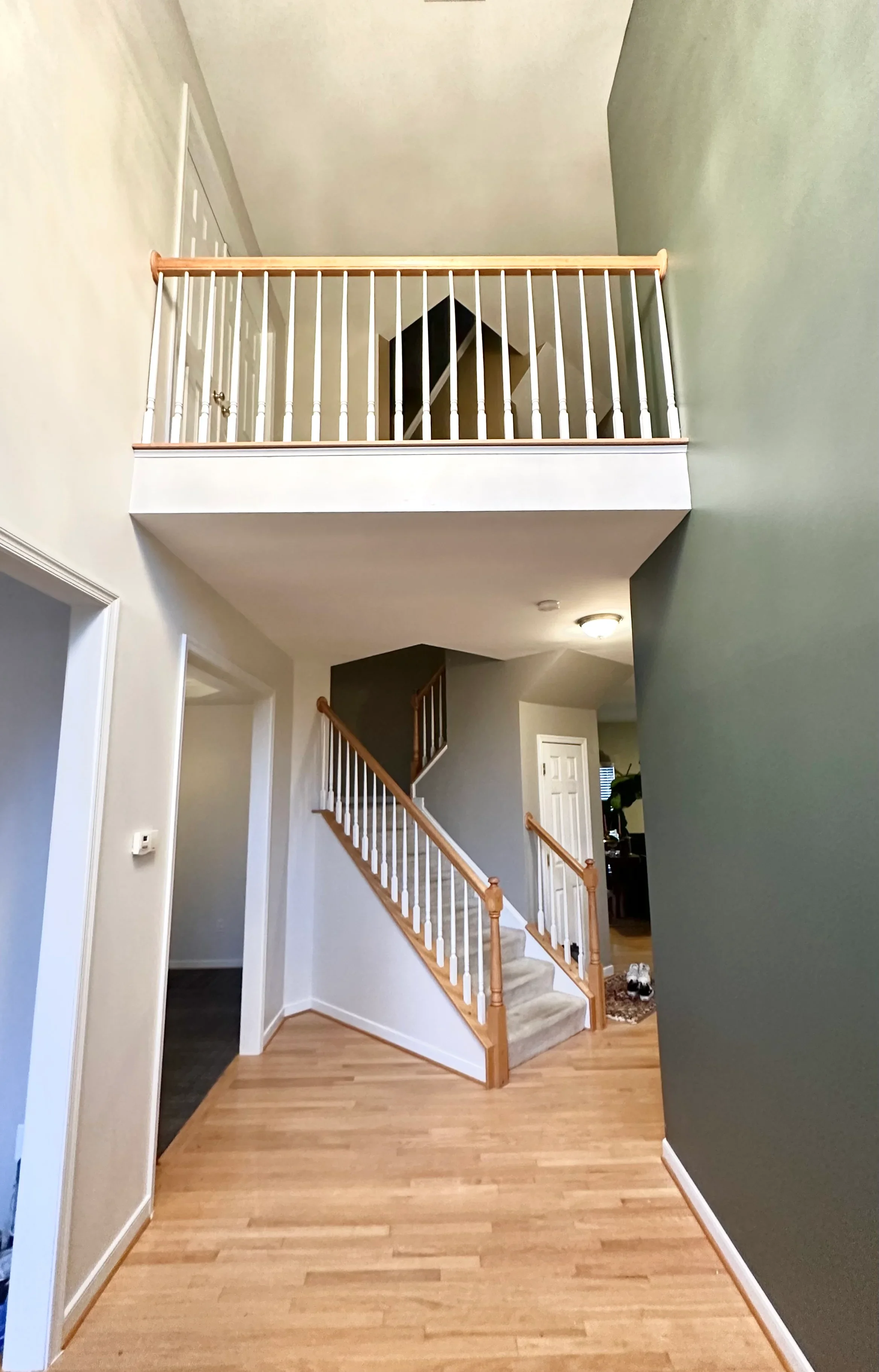 White painted stairwell with wood railings, gray accent wall, and loft railing above