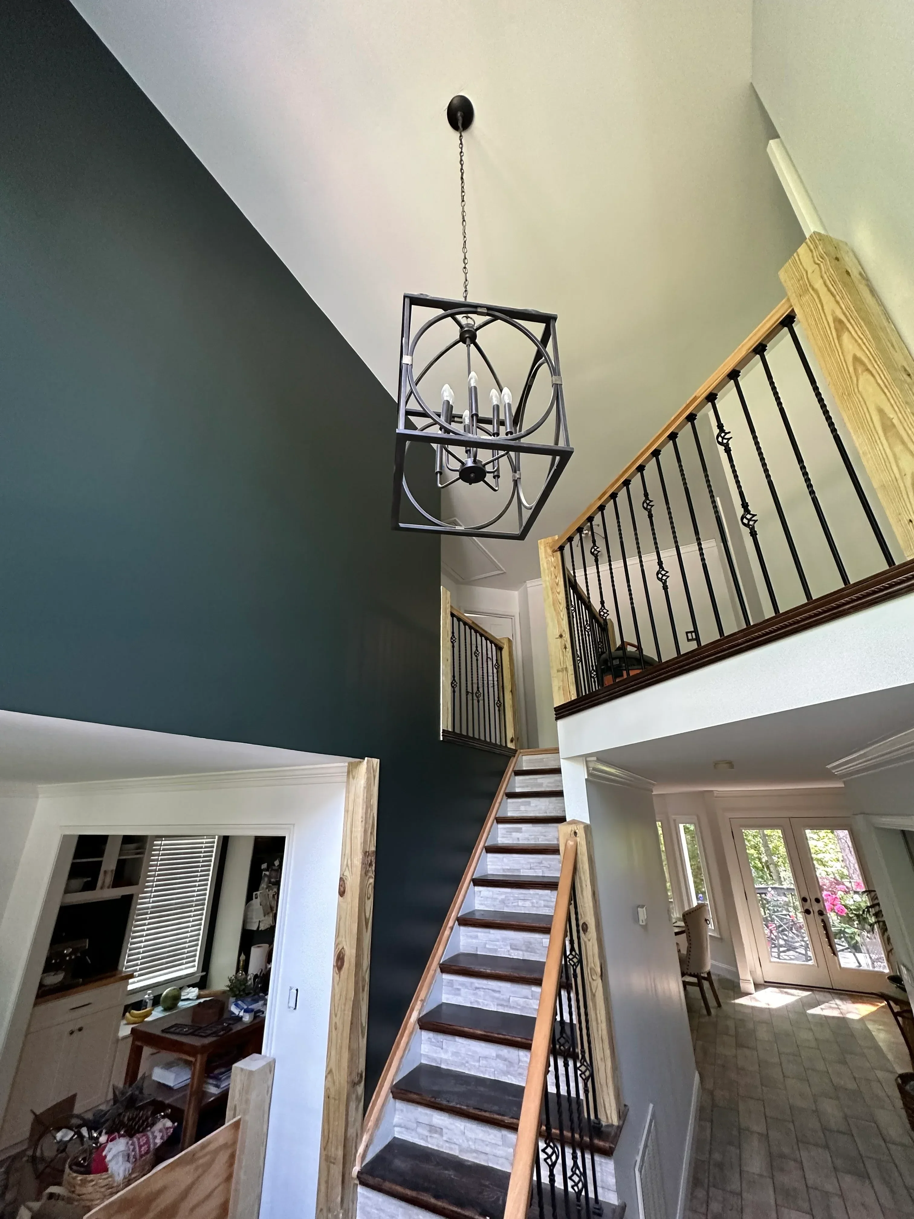 Bedroom with teal accent wall, cream upper walls, white trim, and painted ceiling beams