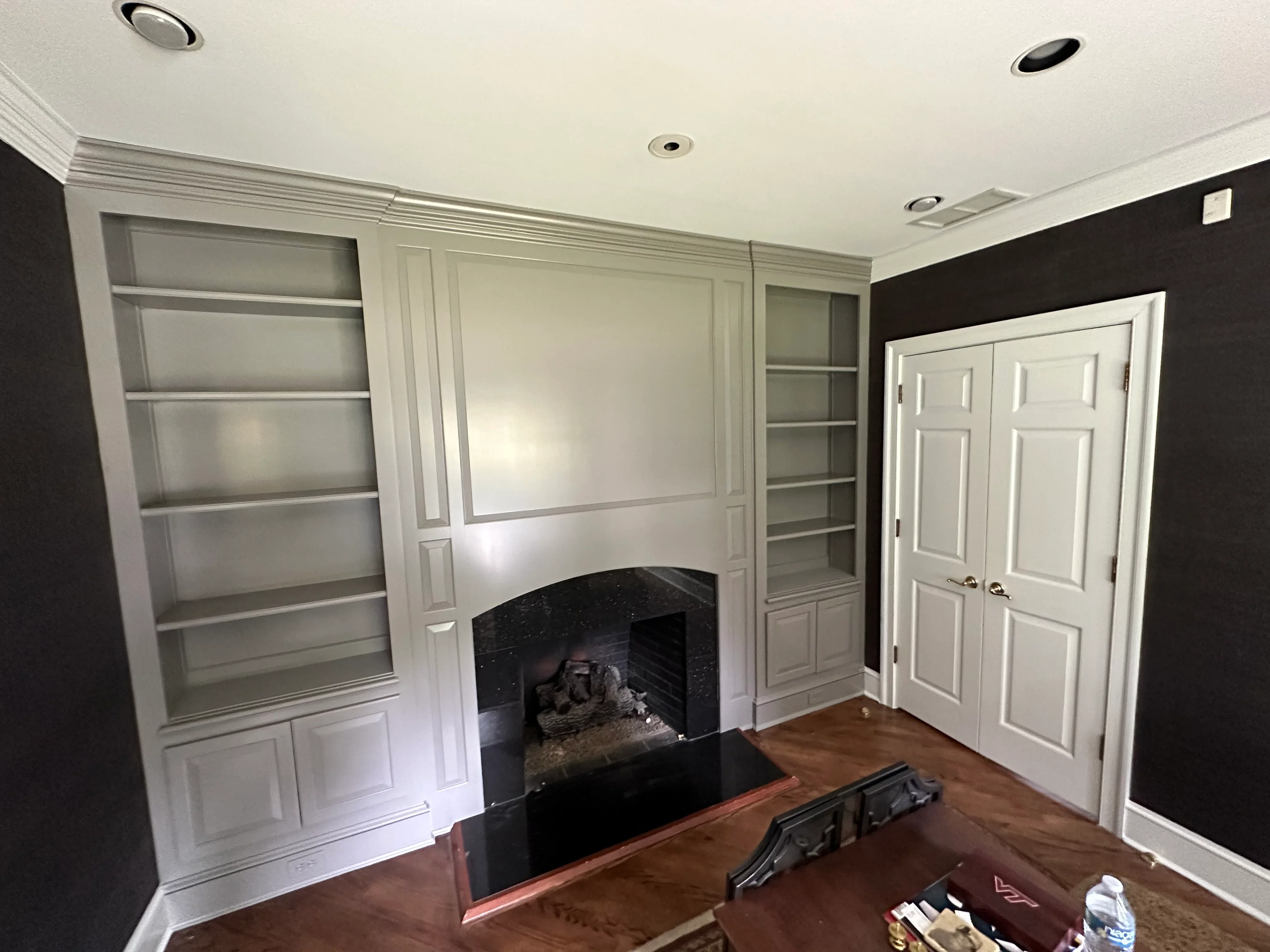 White built-in shelving and fireplace surround with black accent wall and recessed lighting