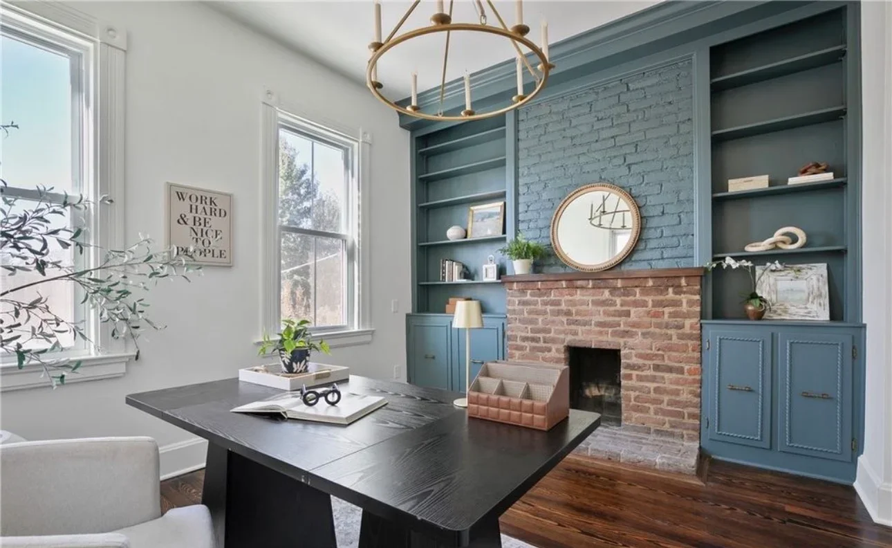 Blue-green painted built-in cabinetry with shelving around brick fireplace in home office