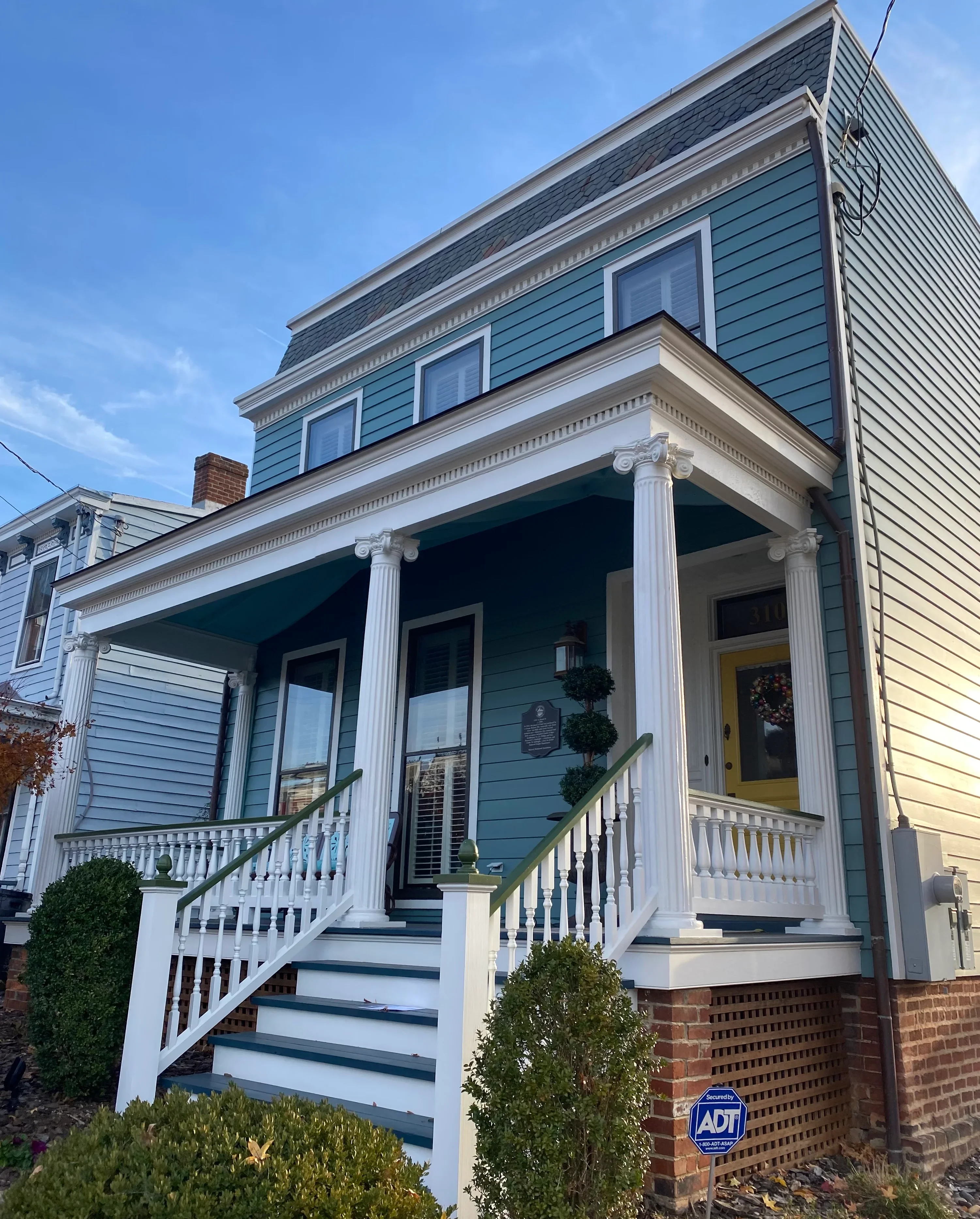 Blue siding with white trim, columns, and railings on historic home front porch