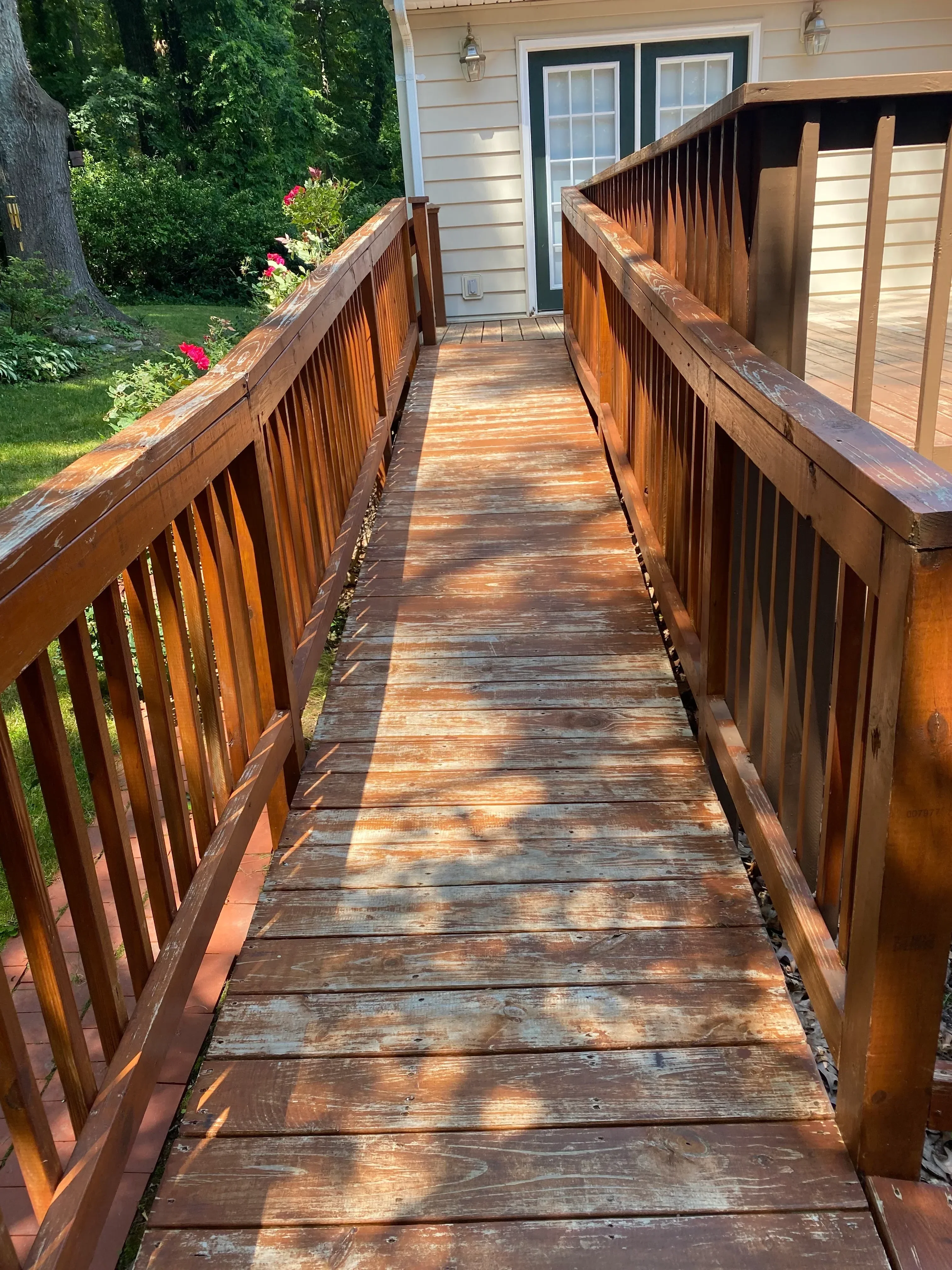 Stained wooden deck with exposed beam pergola and weathered fence panels